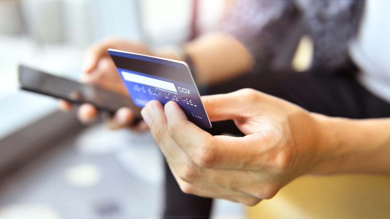person holding their credit card and cell phone